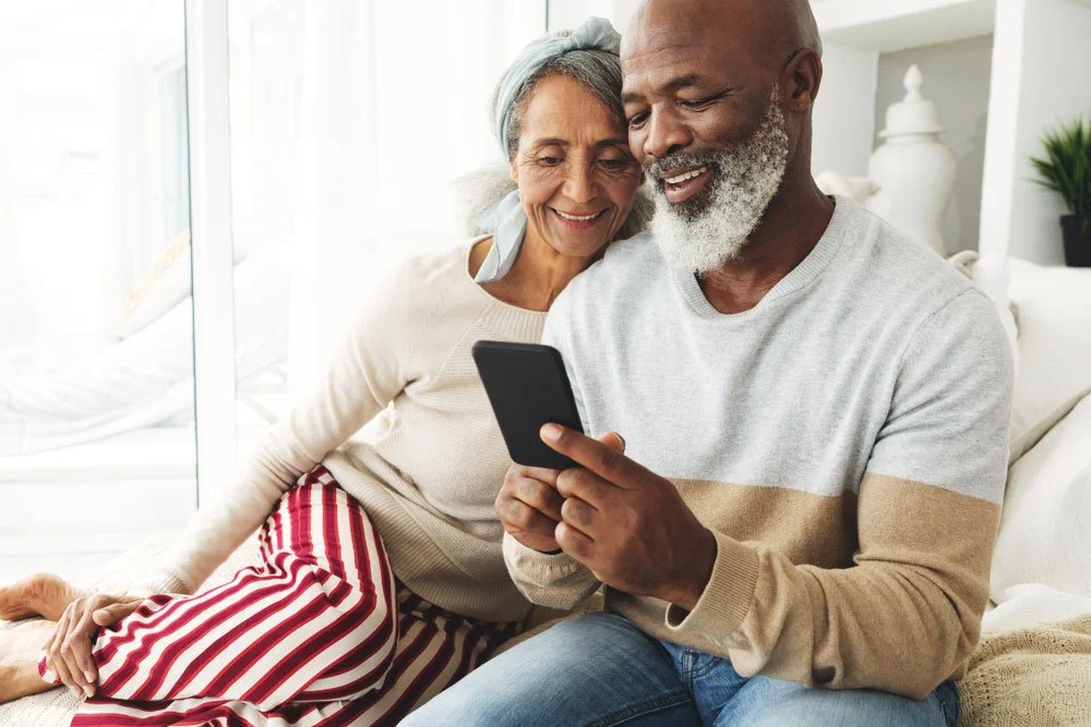 Two seniors sitting on the couch and looking at a smartphone