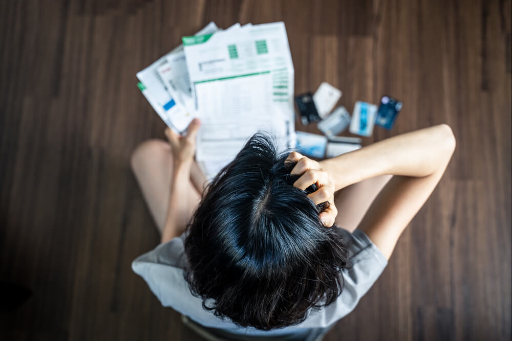 a girl sitting on the floor surrounded by bills and credit cards in a pile around her