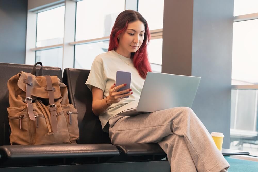 Asian woman freelancer with coffee and laptop working at an airport gate
