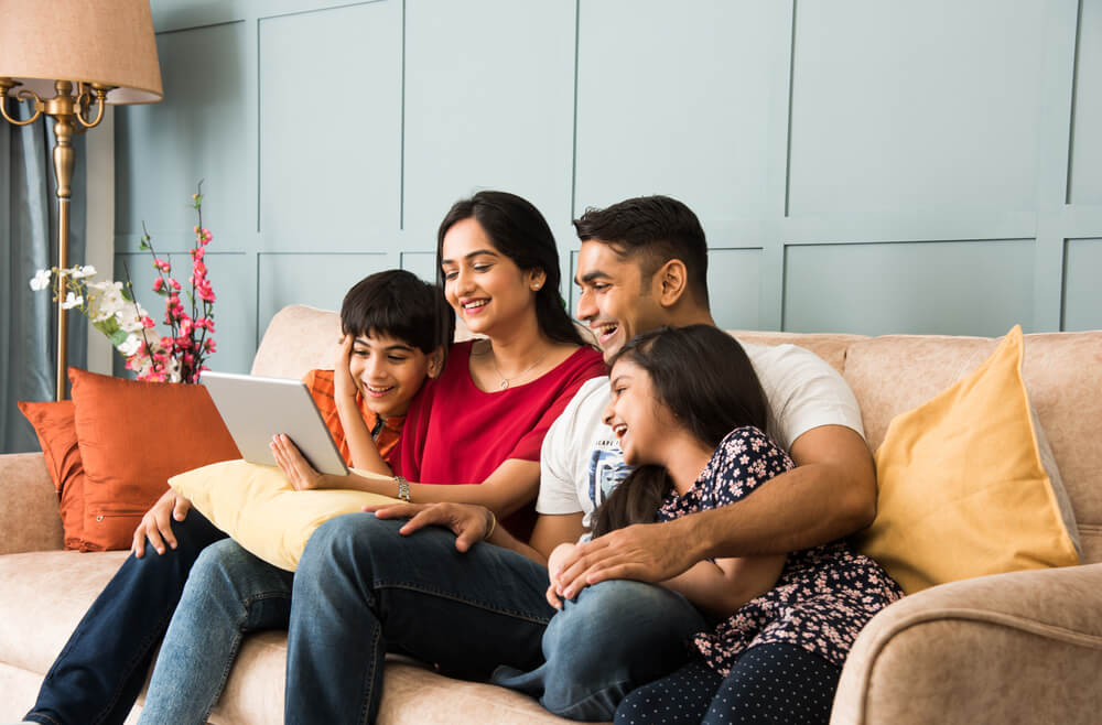 Family sitting on sofa and using tablet to browse home listings