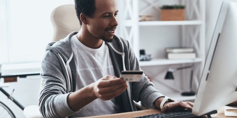 A man online shops on his desktop computer using his credit card